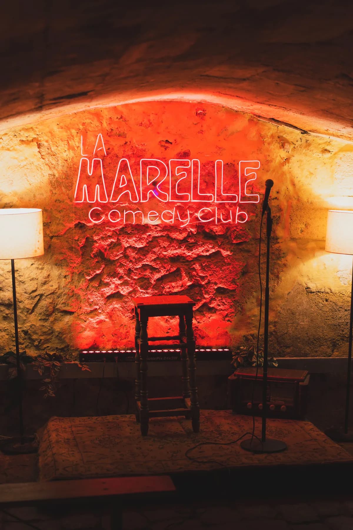 Scène format comedy club avec enseigne néon La Marelle, micro et tabouret — privatisation à Bordeaux